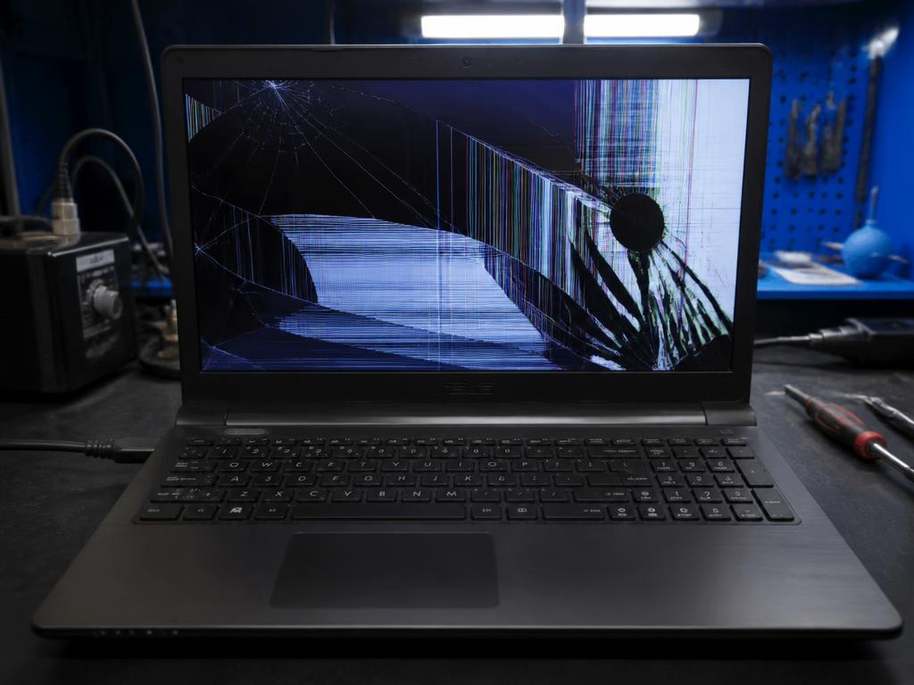 Laptop with a cracked LCD showing broken lines before repair